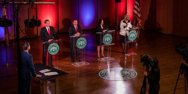 The candidates of the Jacksonville mayoral race at their podiums on stage.